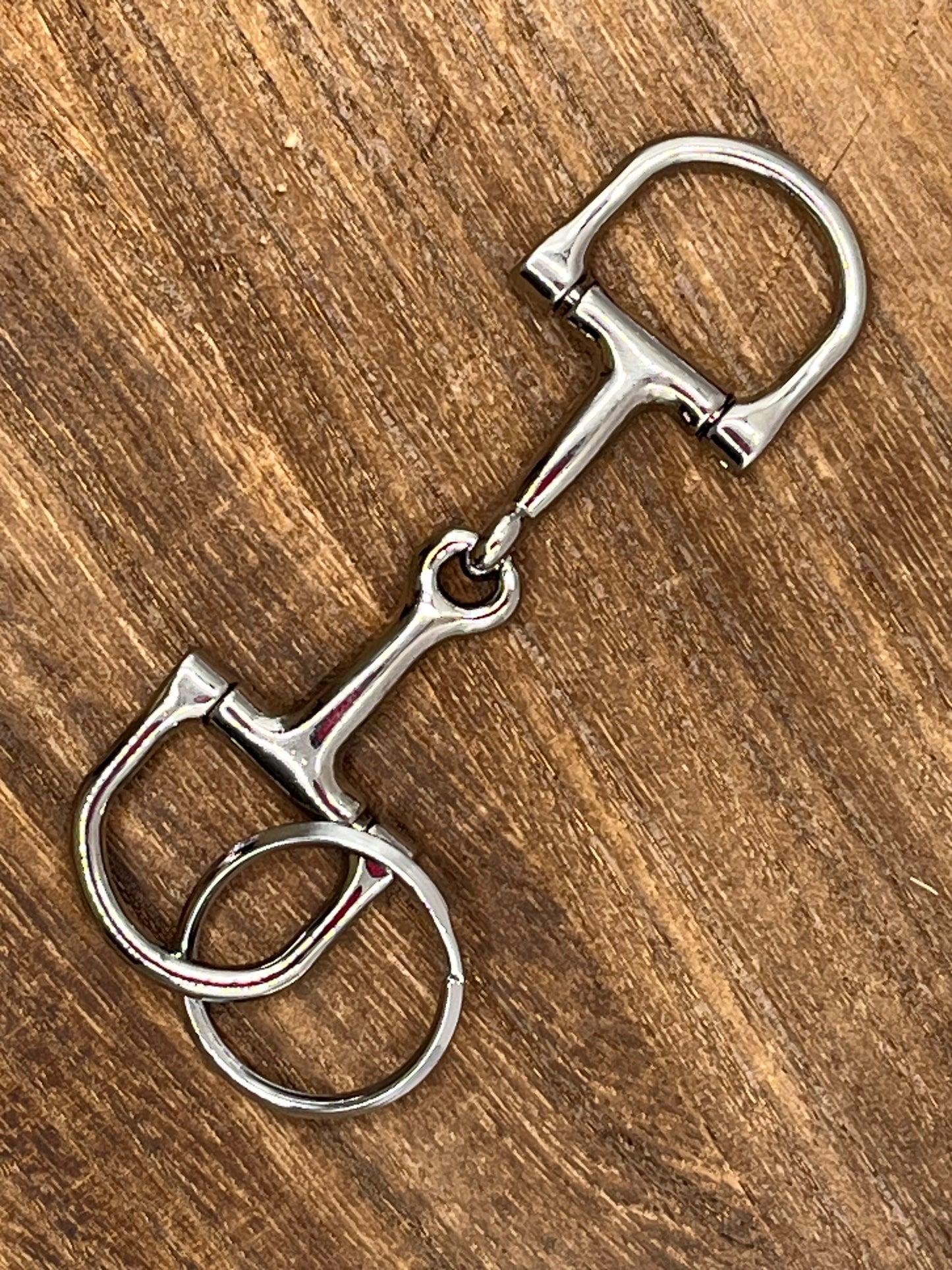 Metal horse bridle bit keyring on a wooden surface