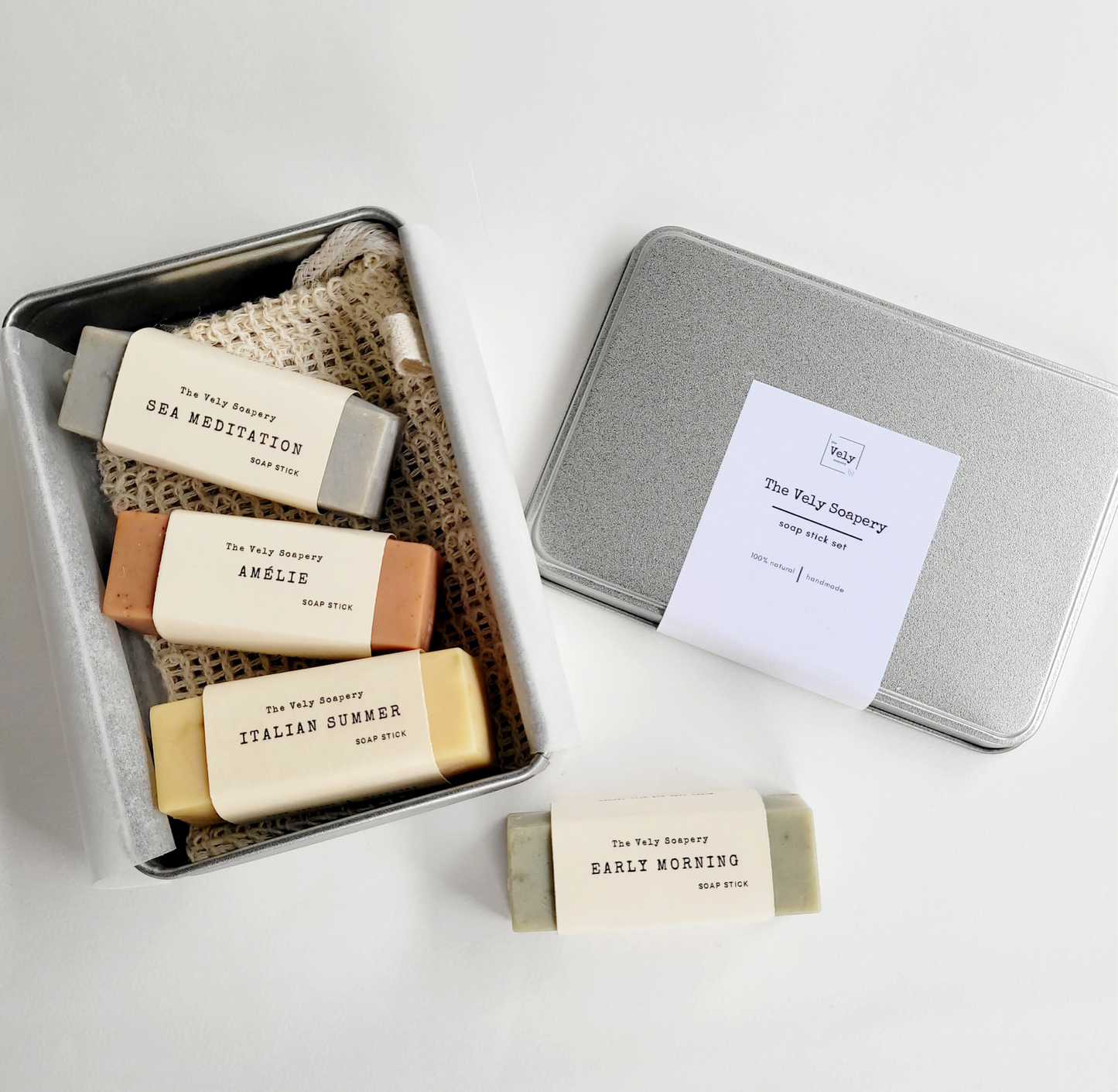 silver metal box which is opened and inside are 4 rectangular bars of soap , each a different colours and scents.