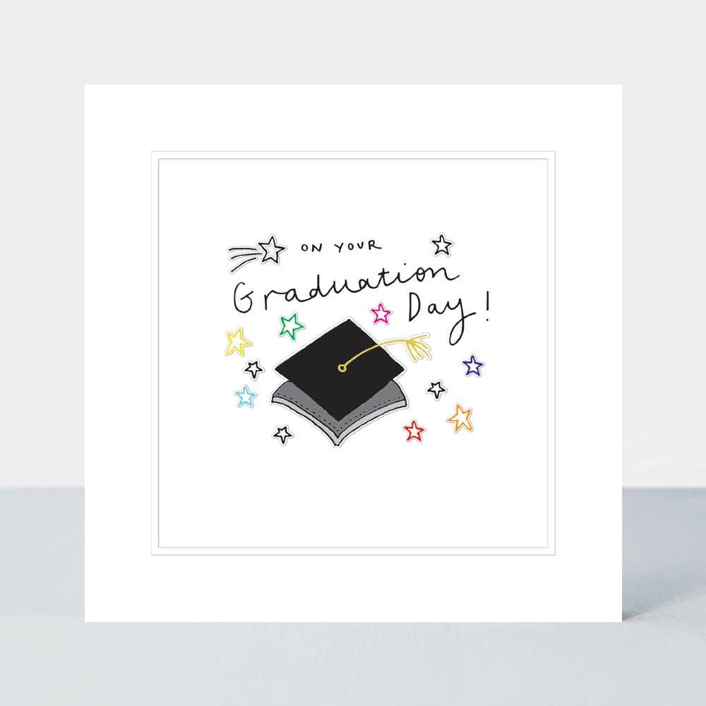Greeting vard with the picture of a mortar board hat on it some stars in yellow red blue stars on the front, with the wording On your Graduation Day