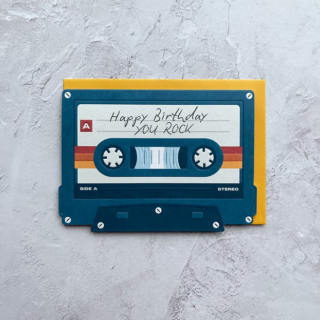 Cassette tape-shaped birthday card with 'Happy Birthday You Rock' text on a textured gray background