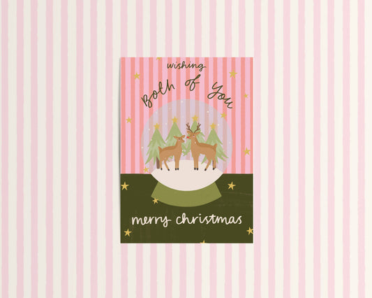 Christmas card with reindeer and trees on a pink and white striped background