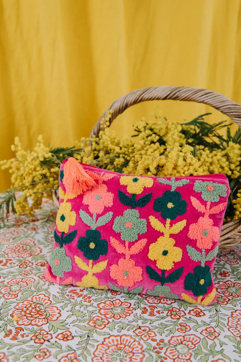 medium size pink velvet  pouch with zip and yellow orange and navy flowers  on the front. With a orange tassel on the zip.