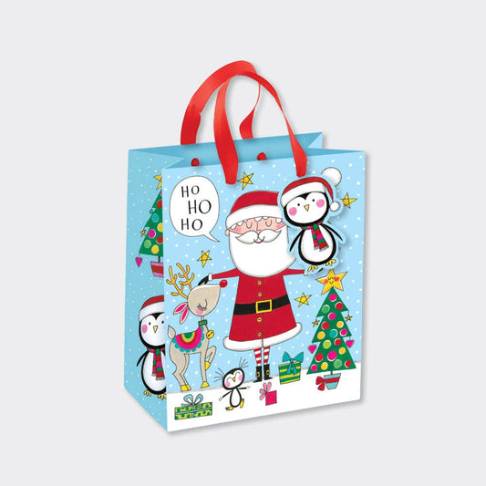 Christmas-themed gift bag with Santa Claus, reindeer, and penguins on a light blue background.