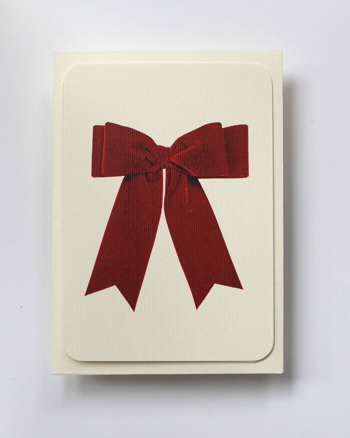 Greetings Card with a Red Velvet looking bow on the front. White Background.    White Envelope.