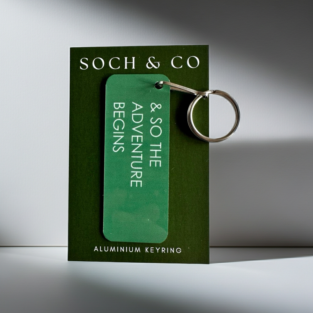 Green keyring with the phrase & so the adventure begins on a 'Soch & Co' branding on a matching card