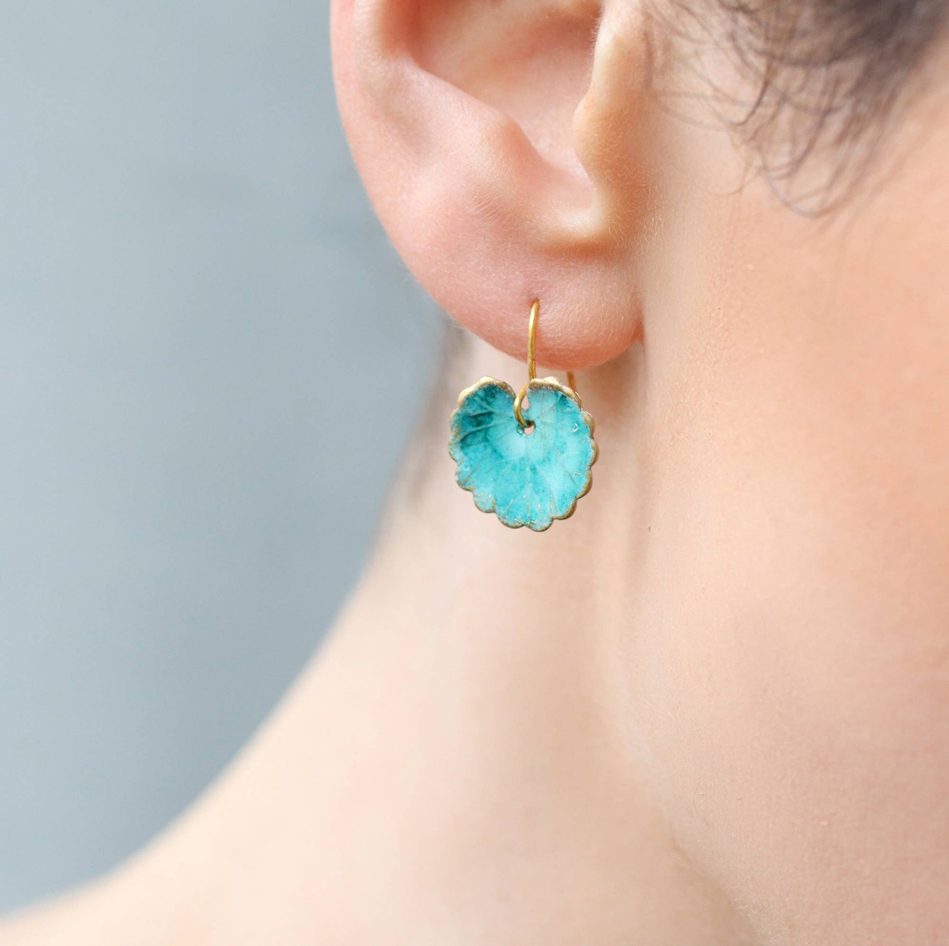 close up image of the gold turquoise leaf earrings being worn 