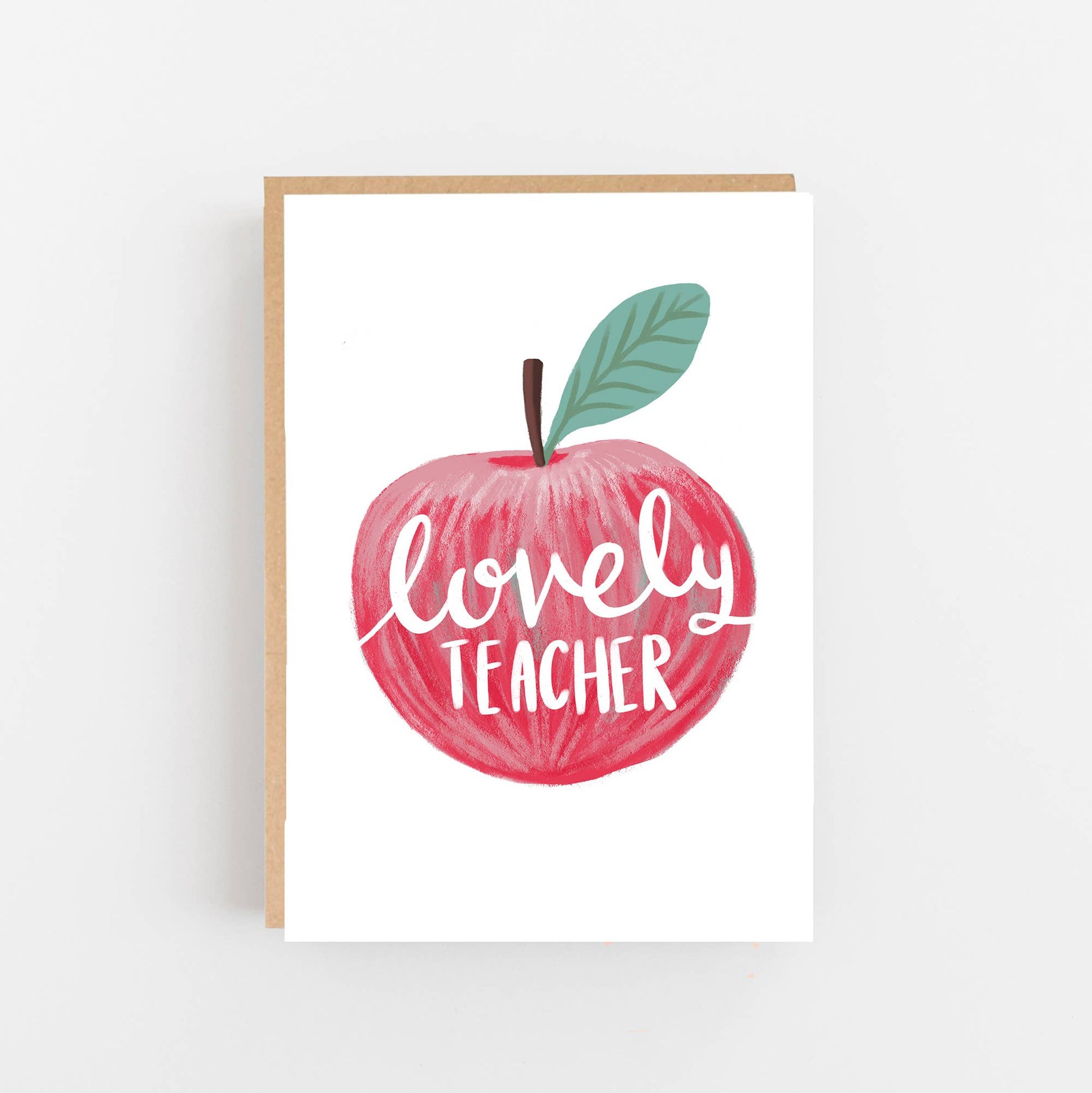Greeting card featuring a hand drawn red apple on the front with the words lovely teacher written in white in the centre of the apple. The card is blank inside for your own message and comes with a kraft envelope.