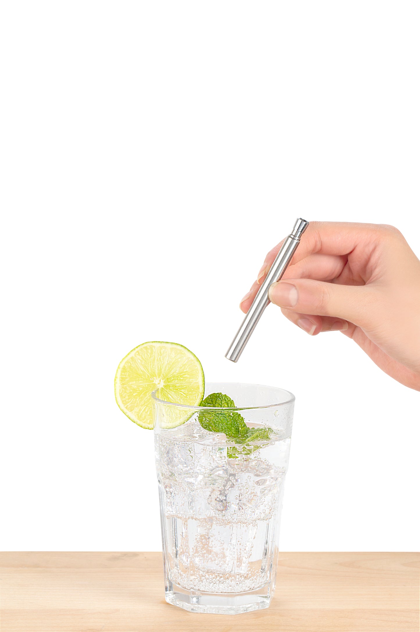 image shows the travel straw being used in a glass of sparkling water