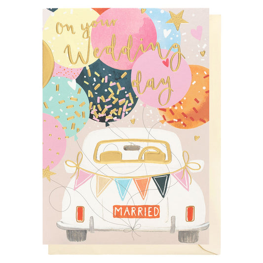 Wedding card with the back of a car in the middle of the card with pastel coloured balloons with gold sprinkles on some of the balloonsand pastel bunting on the back of the card saying MARRIED. Gold foil writing on the front says on your wedding day
