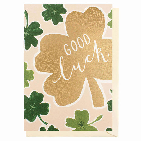 Good Luck Card with green four leaf clovers on a big gold foil  four leaf clover in the middle with white writing saying Good Luck. Pale beige envelope
