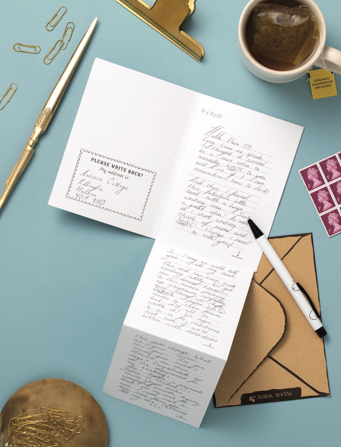 Open letter with handwritten text on a blue surface with stationery items.