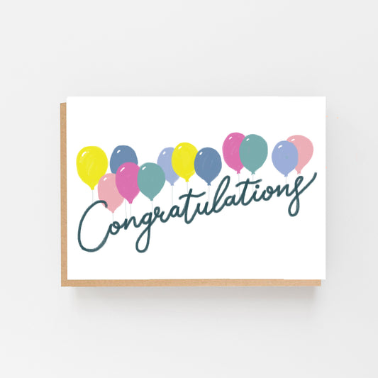 Greeting Card in Landscape with a White Background with a row of pastel coloured balloons all across the centre of the card. With the words Congratulations in black italics. 