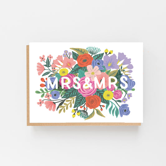 Wedding Card with the words MR & MRS in white in the middle of the card which is displayed landscaped . the words are surrounded by multi coloured flowers. Brown Kraft envelope.