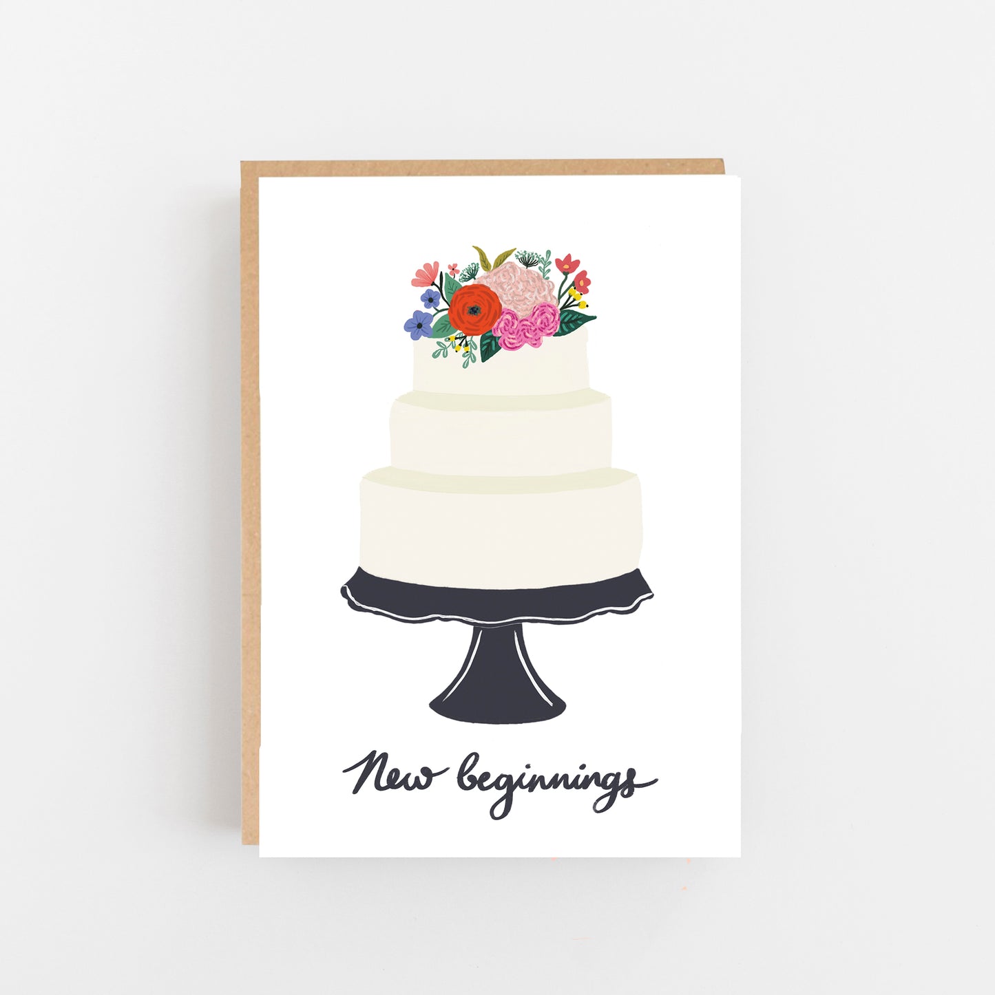 Wedding Card white background with a cake on a black cake stand bunch of flowers on top of the cake underneath the cake stand the words new beginnings in Black. Brown Kraft envelope.