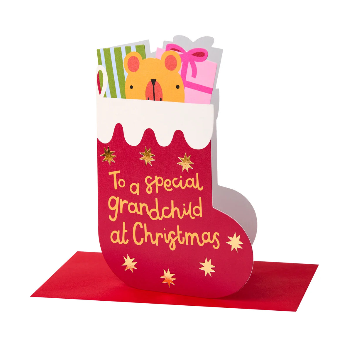A 3D pop-up Christmas stocking card featuring a red stocking with gold glitter stars and the text 'To a special grandchild at Christmas' in gold script. A yellow teddy bear peeking out of the top holds wrapped presents, set against a clean white background with a red base sheet.