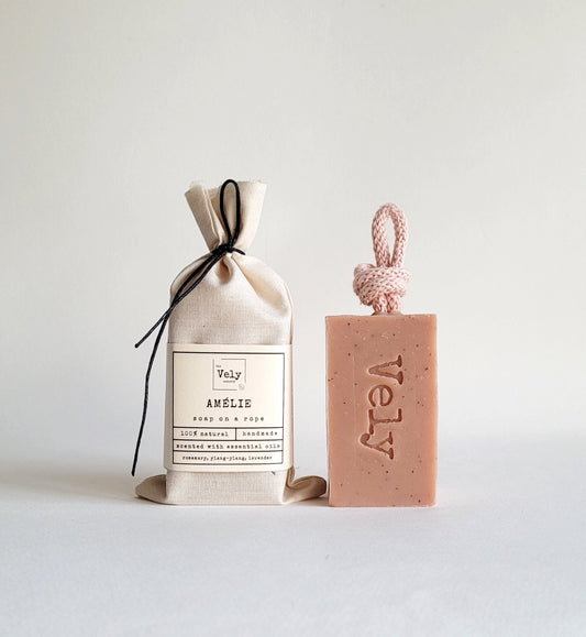 Pink soap with pink rope. the fragrance is amelie. The hessian bag that the soap comes in is shown to the left of the soap. the word Vely is etched into the soap bar.