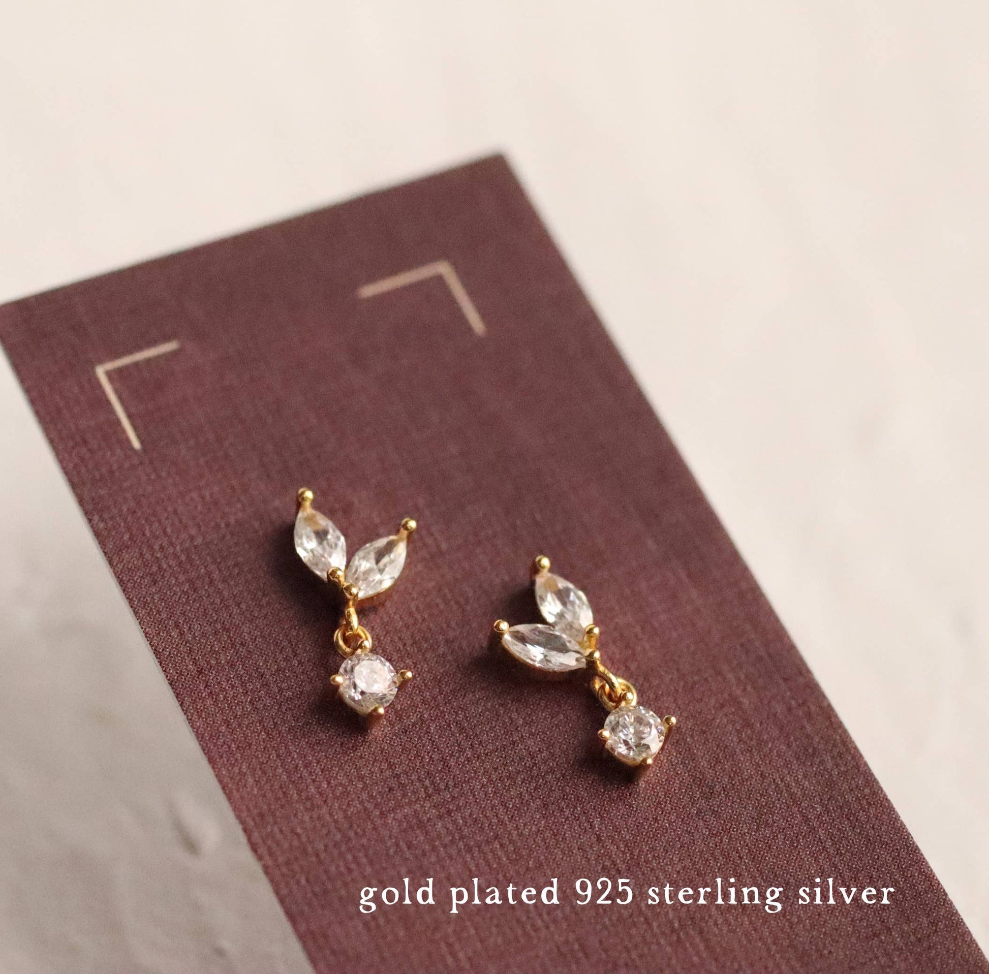 close up image of a pair of crystal drop earrings. each one has to pear cut crystals and one round drop.