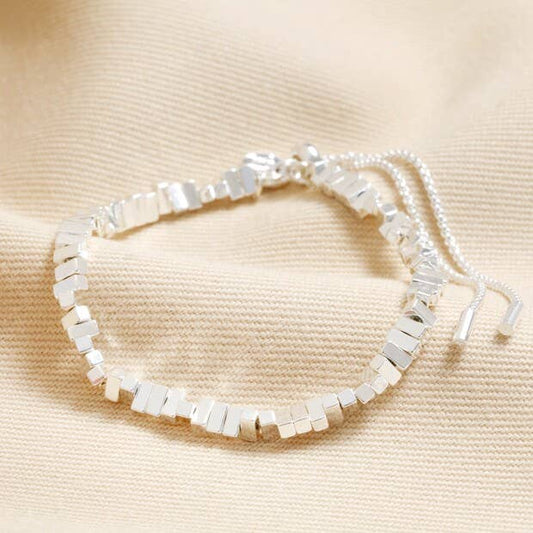Silver beaded bracelet on a beige fabric background