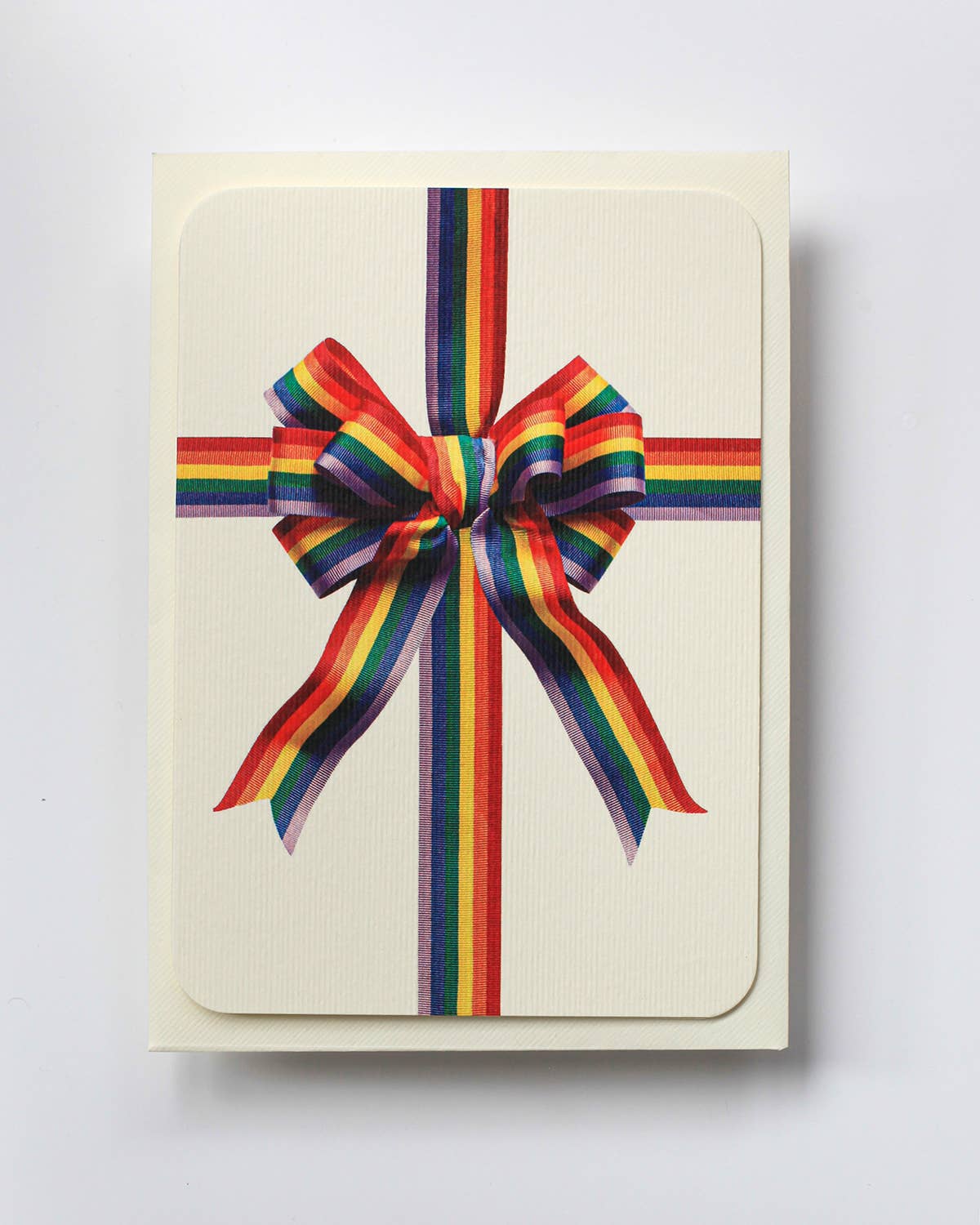 Greetings Card with a Multicoloured Ribbon looking bow on the front. In Pride colours purple blue green yellow orange and red. Looks like real material but it is an image  White Background.  White Envelope