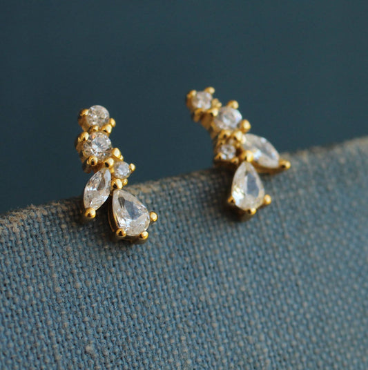 close up image of a pair of earrings with 5 crystals of various shapes and sizes and will gold surrounds