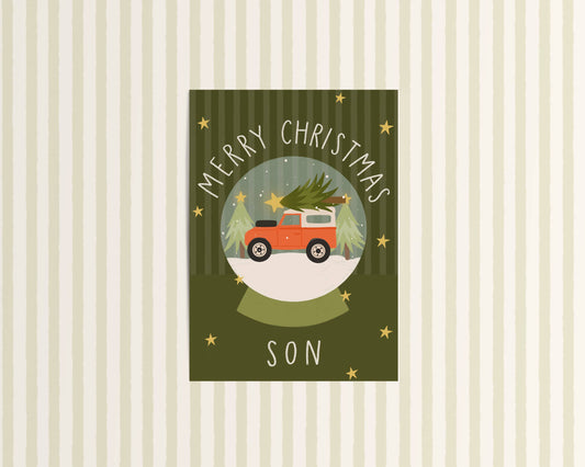 Christmas card with a red truck carrying a Christmas tree, text 'Merry Christmas Son' on a striped background.