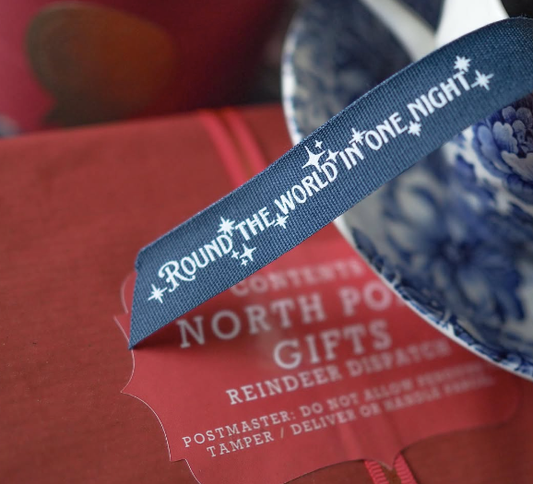 Dark navy christmas ribbon with round the world in one night printed in white and repeated along the full length 