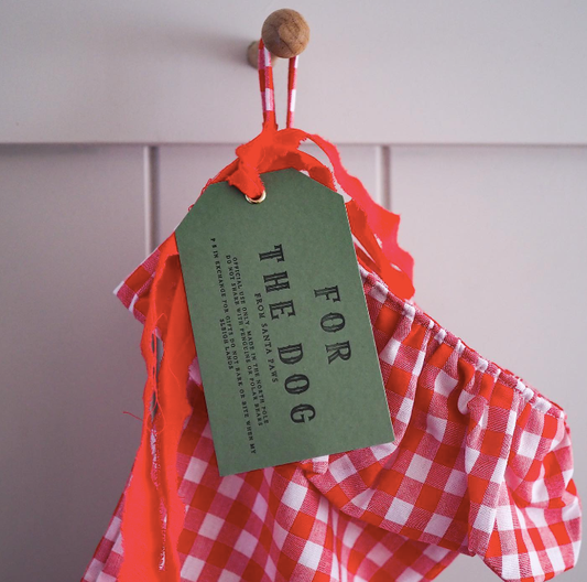 A set of 3 christmas gift labels that have  For the Dog from Santa Paws on each label. The background colour is dark grey and the writing is in Black capital letters.