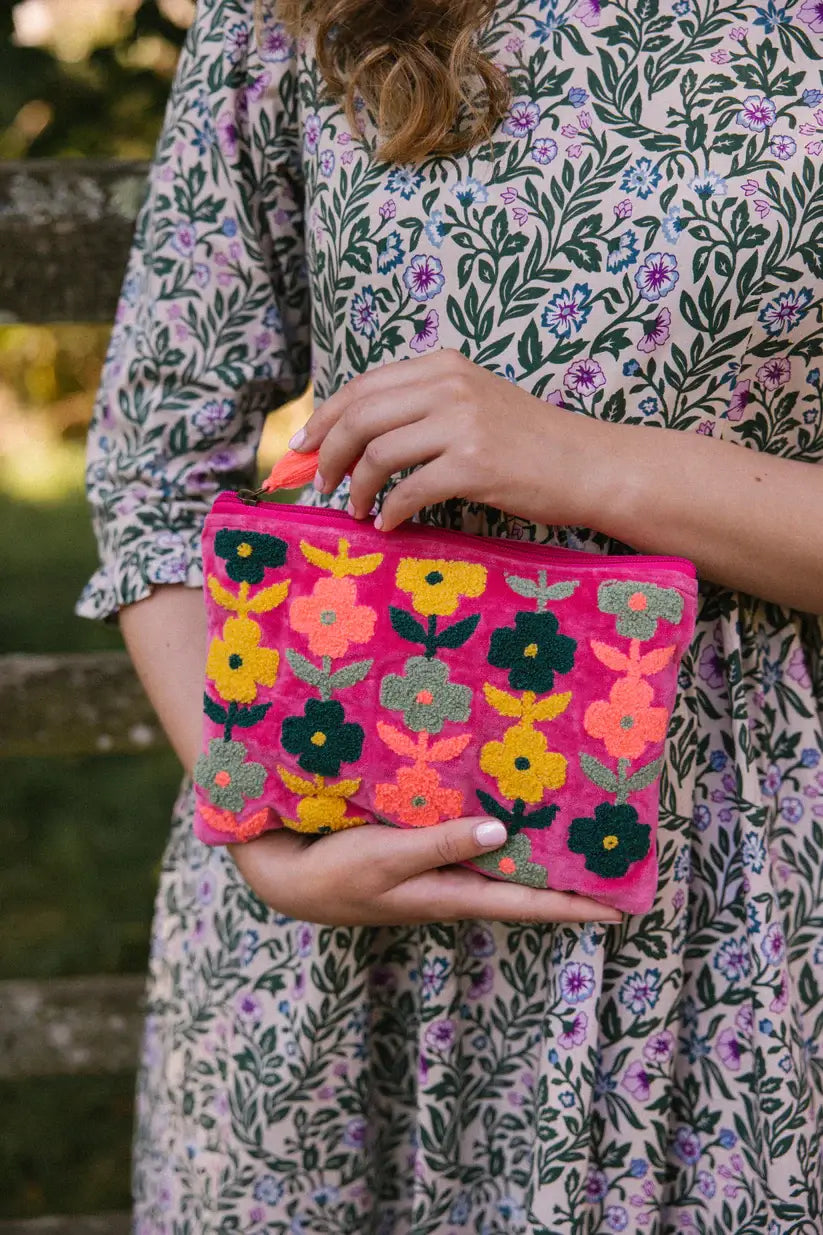 medium size pink velvet  pouch with zip and yellow orange and navy flowers  on the front. With a orange tassel on the zip.