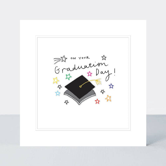 Greeting vard with the picture of a mortar board hat on it some stars in yellow red blue  stars on the front, with the wording On your Graduation Day