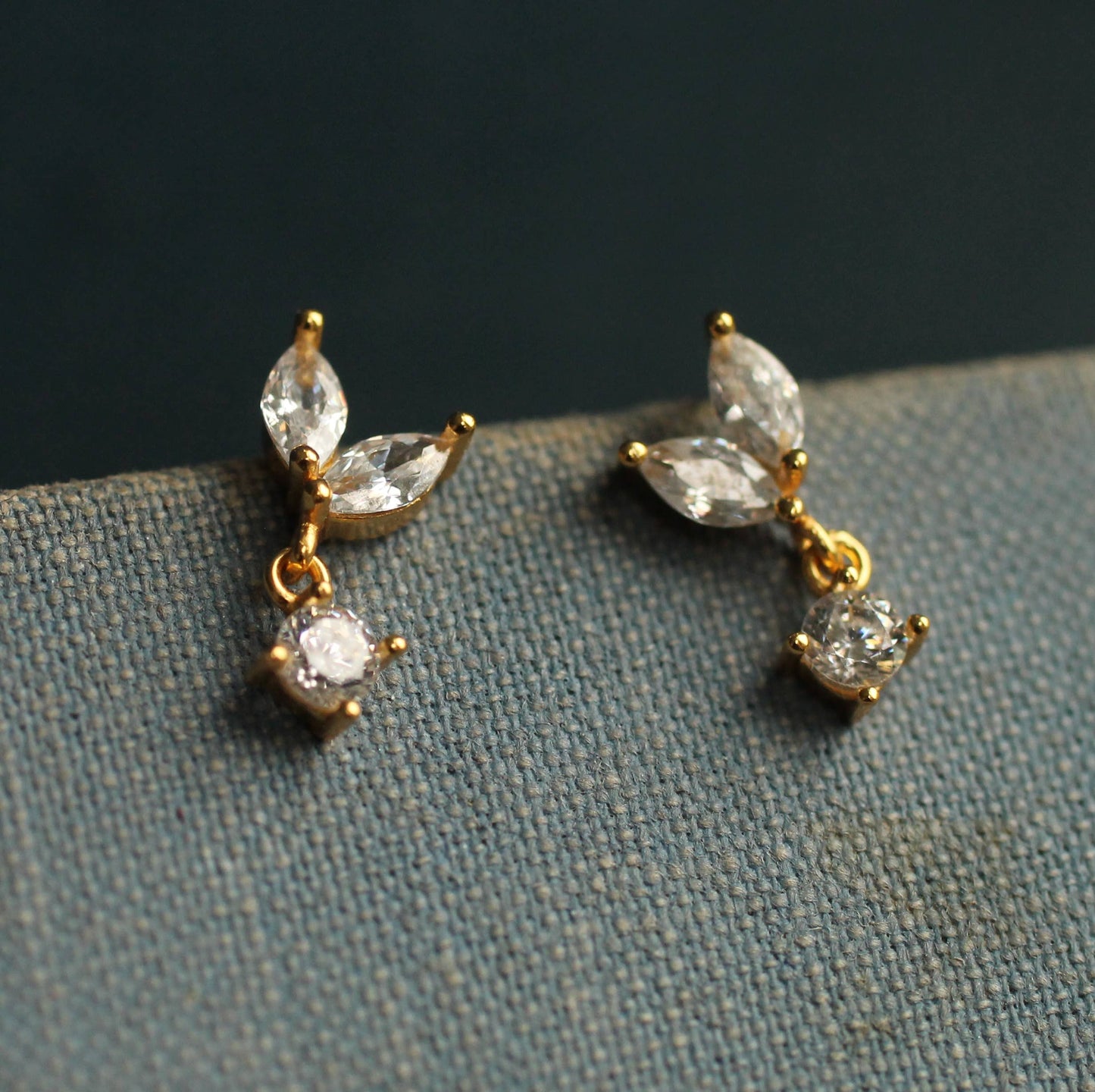 close up image of a pair of crystal drop earrings. each one has to pear cut crystals and one round drop.
