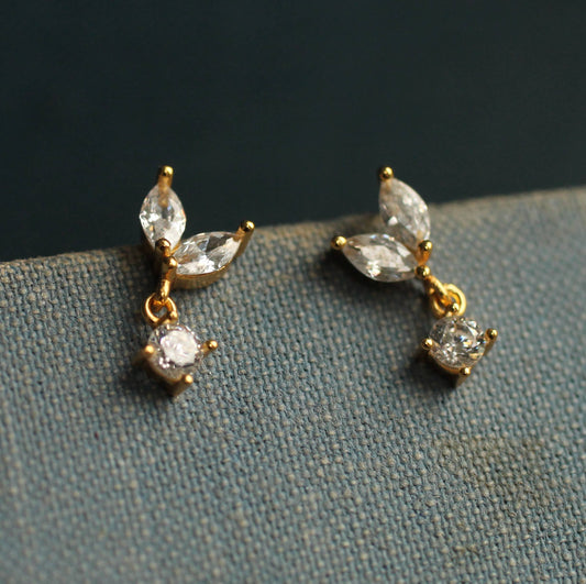 close up image of a pair of crystal drop earrings. each one has to pear cut crystals and one round drop.